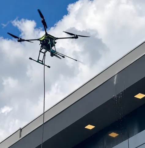 Drone de limpeza em altura sobrevoando um prédio comercial
