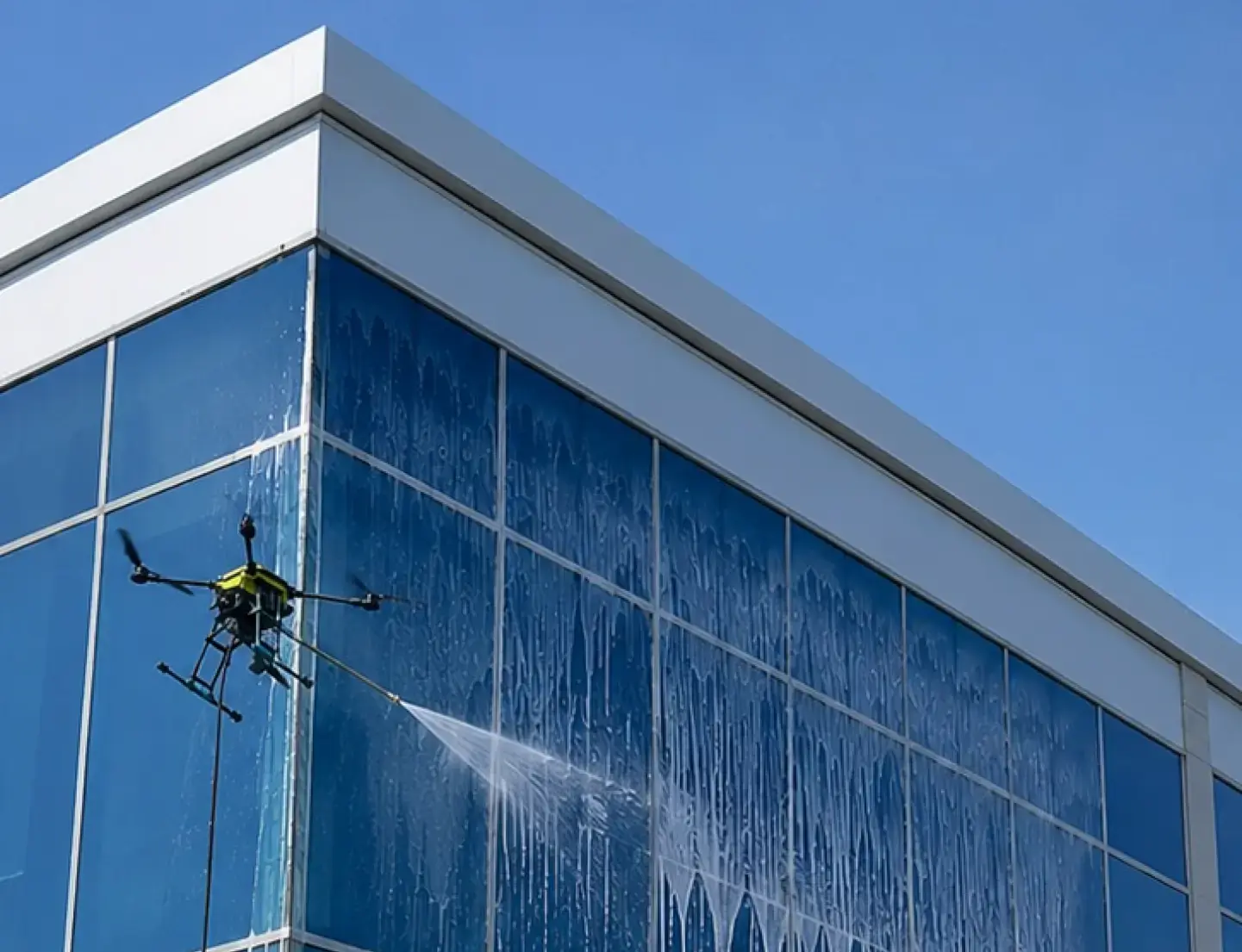 Drone realizando a limpeza de uma fachada de vidro em altura