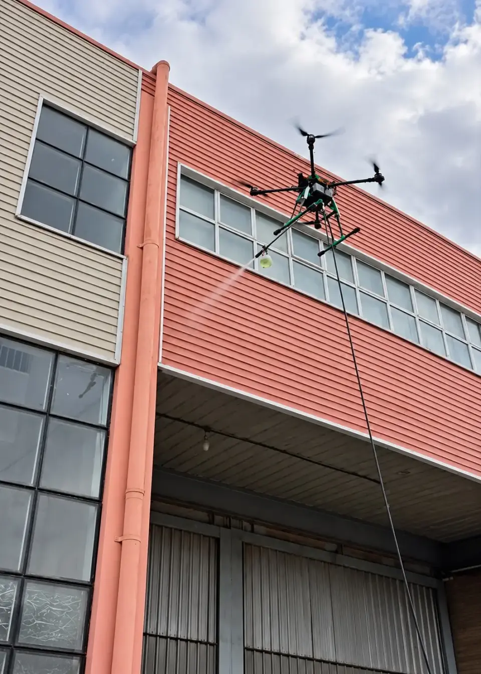 Drone em voo diante da fachada do galpão com janelas