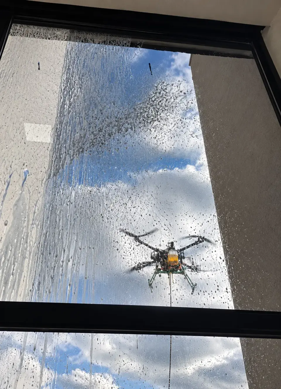Jato de água do drone atingindo a janela de vidro vista de dentro