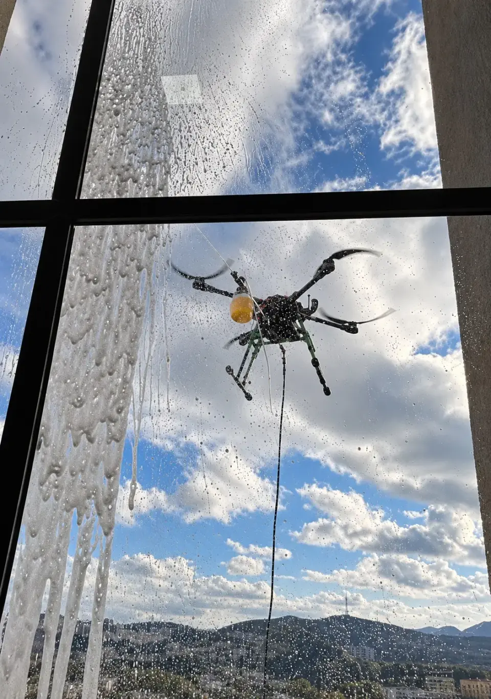 Drone de limpeza visto de dentro de um apartamento através do vidro