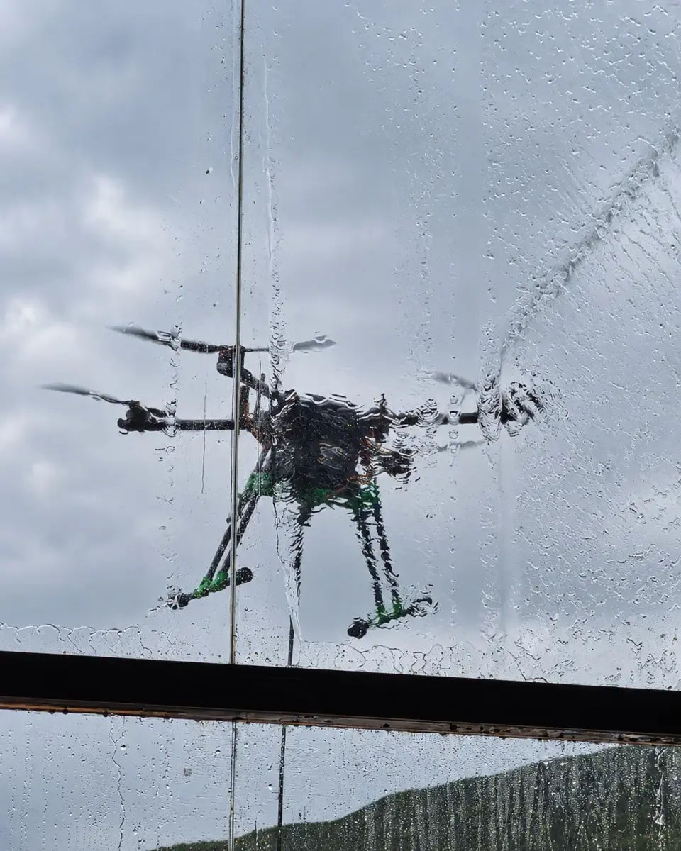 Detalhe do drone de limpeza visto através do vidro molhado